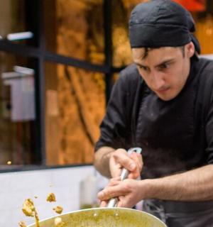 一名男子在厨房里用锅准备食物