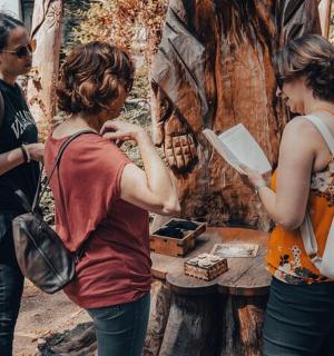 three women standing in front of a painting of a tree