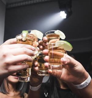 a group of people holding up drinks with lime slices on them