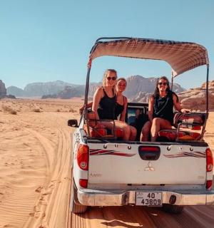 tři ženy sedící v zadní části džípu v poušti