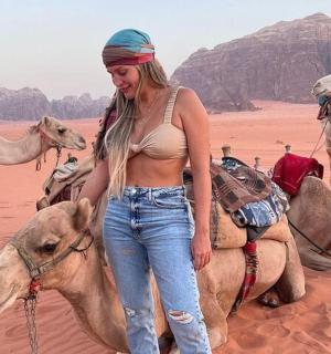 žena stojící na velbloudovi v poušti