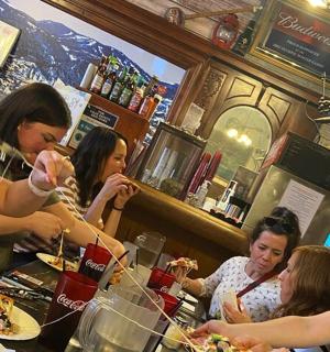 a group of people sitting at a bar eating pizza