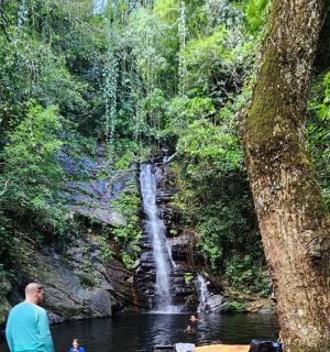 a man standing in the water in front of a waterfall