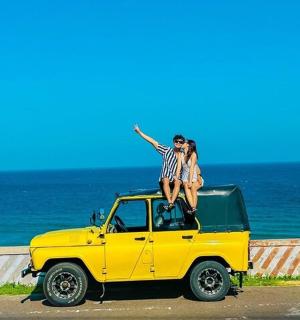 一名男子和一名女子坐在一辆黄色汽车顶上