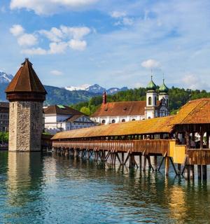 a bridge over the water in a town with mountains