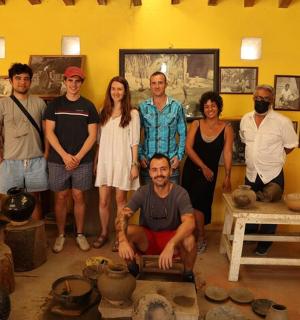 一群人在摆放着陶器的房间里摆姿势拍照