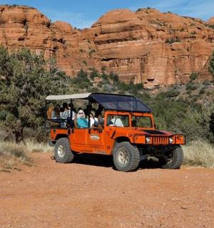 oranžový džíp s lidmi jedoucími v poušti