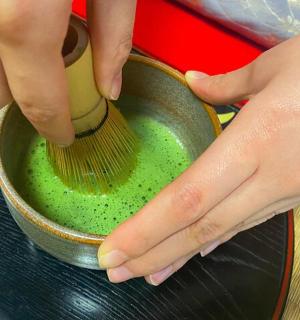 a person holding a brush in a pot with green liquid