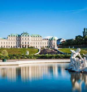 a large building with a fountain in the water in front of it