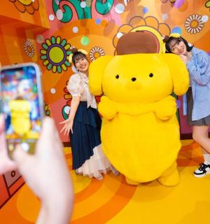 一个人正在给一只黄色的大泰迪熊拍照