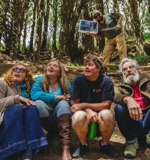 一群人坐在树林里的一块岩石上