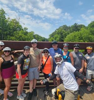 cilvēku grupa pozē fotografēšanai uz tilta