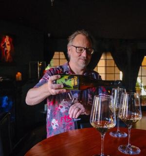 a man pouring wine into glasses at a table