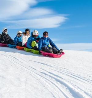 a group of people riding on a sled down a snow covered slope