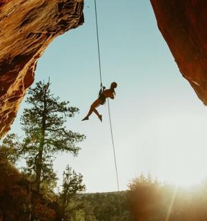 muž na laně visící z útesu