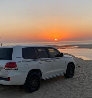 bílý kamion zaparkovaný na pláži se západem slunce