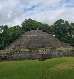 a large pyramid in a field with trees in the background