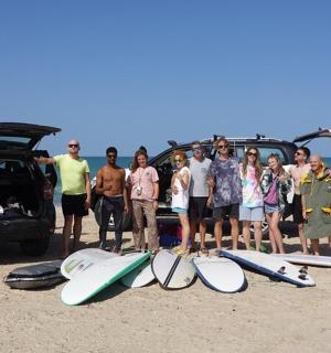一群人站在海滩上，手里拿着冲浪板