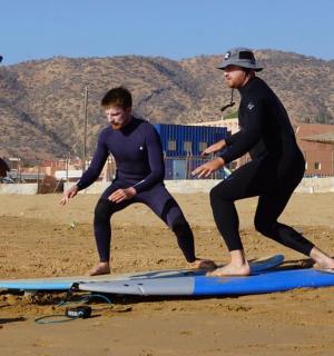 三个男人站在海滩上的冲浪板上