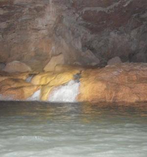 a pool of water in a cave with a waterfall
