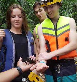 a group of people standing next to a woman holding a spider