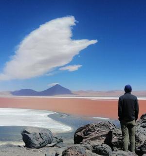 a man standing on some rocks looking at the water