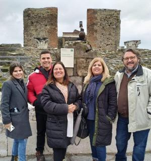 skupina lidí stojící před ruinami