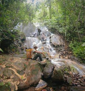 a man sitting on a rock in front of a waterfall