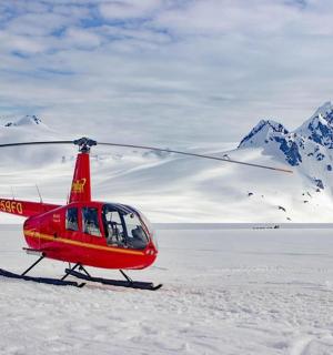 一架红色直升机停在山前的雪地里