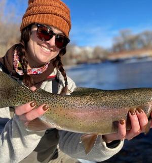 一位女士在湖边牵着一条褐鳟鱼