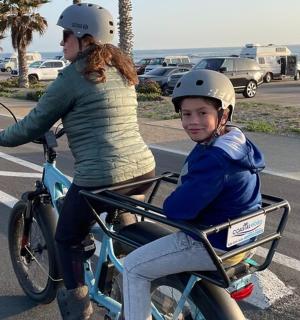 一名女子骑着摩托车，篮子里装着孩子