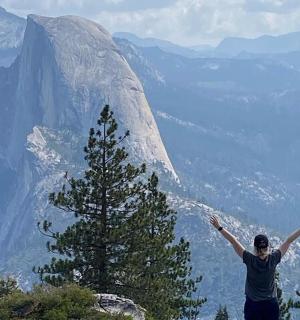 a man standing on top of a mountain with his arms up