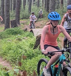 a group of people riding bikes on a trail in the woods