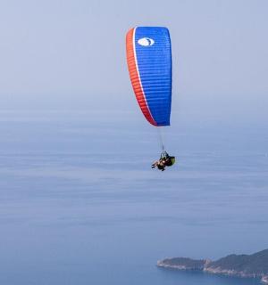 a person riding a parachute in the air over the water
