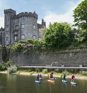 skupina lidí na paddleboardech ve vodě před hradem