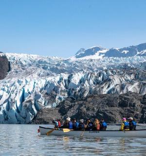 skupina lidí v lodi před ledovcem