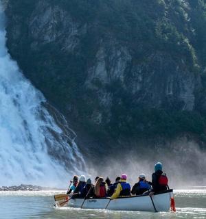 skupina lidí v lodi před vodopádem