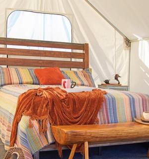 ložnice s postelí a lavicí ve stanu