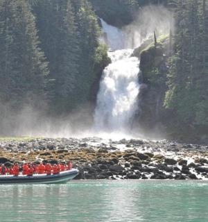 skupina lidí v lodi před vodopádem