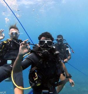skupina tří lidí ve vodě s fotoaparátem