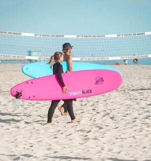 two people standing on the beach holding surfboards