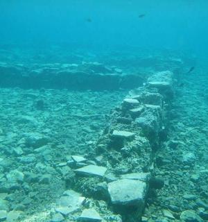a stone wall in the ocean with rocks and water