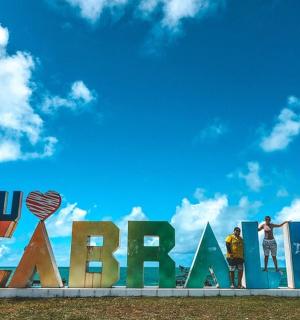 两个人站在海滩上的一块大招牌旁边