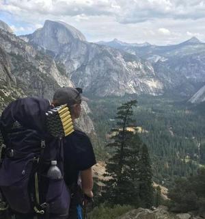 muž stojící na vrcholu hory a dívající se do údolí