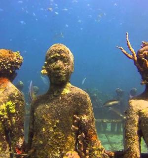 a group ofulptured people standing in front of an aquarium