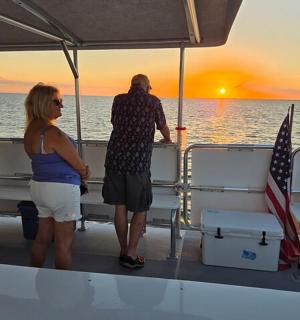 skupina lidí stojící na lodi a pozorující západ slunce