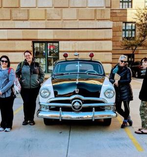 一群人站在一辆旧车旁边