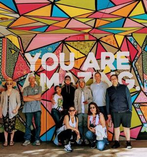 a group of people posing in front of a mural