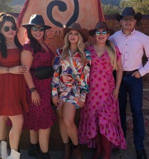 a group of people wearing dresses and hats posing for a picture
