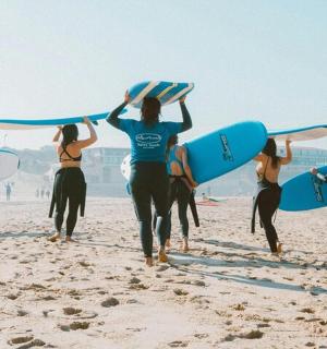 一群人带着冲浪板在海滩上散步